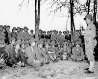 Staff Sergeant Harry Miyamoto instructs men of the 100th Infantry Battalion on the use of the hand grenade at Camp Shelby, Mississippi, shortly after the unit’s arrival. Many of the soldiers were American citizens of Japanese ancestry from Hawaiʻi and former members of the Hawaiian National Guard. January 1943. [Original caption: “Staff Sergeant Harry Mijamoto [sic] Lectures Members of the 100th Infantry Battalion on a Beach,” 1943. Courtesy of NARA. NAID: 404790308.]