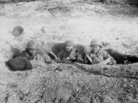 Three soldiers catch up on the news while in a trench in Italy. [Courtesy of Mary Hamasaki]
