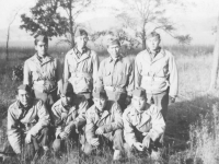 Eight soldiers pose for a photograph in the forest. [Courtesy of Mary Hamasaki]