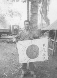 Tom Matsumura holds a Japanese sword and flag while stationed in the Philippines [Courtesy of Florence Matsumura]