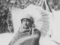 Taken August 9, 1942 at Wisconsin Dells Indian Reeservation (well sort of).  They don't live in the tepees pictured here but in round semi-circle huts.  The tent in left background is also for living quarters.  The Indian girl on the right background is selling bead works made by them on the stand.  [Courtesy of Jan Nadamoto]