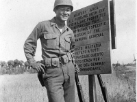 James Funakoshi poses by a warning sign at 100th Battalion camp in Italy [Courtesy of Robert Arakaki]