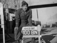 Ernest Kanno poses with his Battalion's sign in Italy [Courtesy of Robert Arakaki]