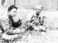 Shigeru Ushijima from Hilo and Ed Ikuma eat lunch during a break at the firing range at Camp McCoy, Wisconsin, August 1942 [Courtesy of Edward Ikuma]