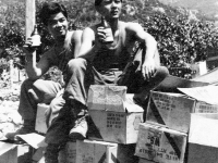 Two soldiers sit on rations and drink beer in Lecco, July, 1945 [Courtesy of Carol Inafuku] Inscription: Lecco July 1945