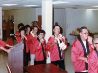 Club 100 Karaoke Kai's first anniversary celebration on March 9, 1984. Masao “Stu” Yoshioka (third from the right) marching onto the stage with other members, wearing the Club 100 Karaoke-kai red happi coat while singing and playing toy instruments. General Chairman and emcee was Richard “Japan” Nakahara (Co. A), Program Chairman was Gladys Kawakami [wife of Eugene Kawakami (Co. A)], Assistant Program Chairman was Donald “Blue” Nagasaki (Co. A), and Masao Yoshioka was in charge of Mic and Music. [Courtesy of Puka Puka Parade (Apr-Jun 1984, Vol. 38 No. 2)]