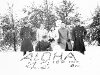 Soldiers and Wisconsin women pose for a group photo in front of the snowman and sign “Aloha ‘42  100 INF. BN. [Courtesy of Goro Sumida]