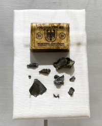 Fragments of American 0.30-06 Springfield cartridges removed from 2nd Lt. Takeichi Miyashiro’s wound, and German matchbox they were stored in. [Courtesy of Jan Sakoda]