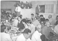 Col. Turner (sitting, far right), listens to Mits Fukuda (standing) at a postwar dinner in Hawaii. [Courtesy of Bob Kainuma]